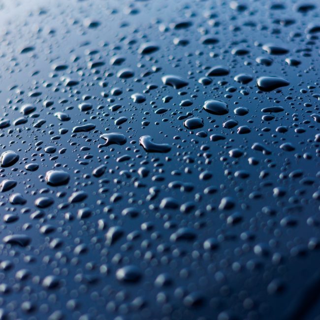 Abstract rain or water drops different size on a blue car hood surface with shiny reflections. Wate